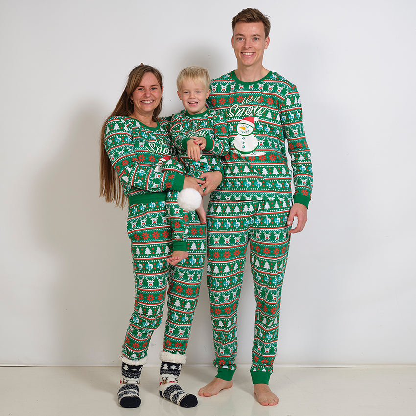 En mand, en kvinde og et barn poserer sammen i hver deres grønne julepyjamas.